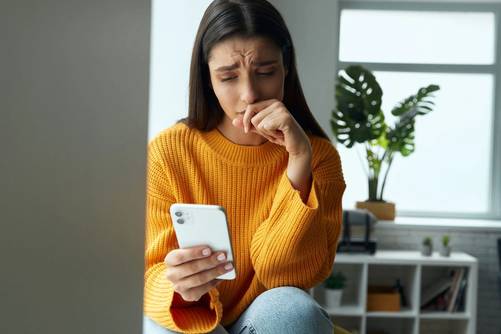 Frau schaut angespannt auf ihr Handy und wartet auf eine Nachricht – typisches Verhalten bei ängstlichem Bindungsstil