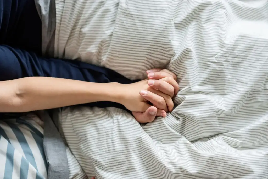 Zwei ineinandergelegte Haende auf einer Bettdecke – Sexualtherapie kostet dasselbe wie Paartherapie